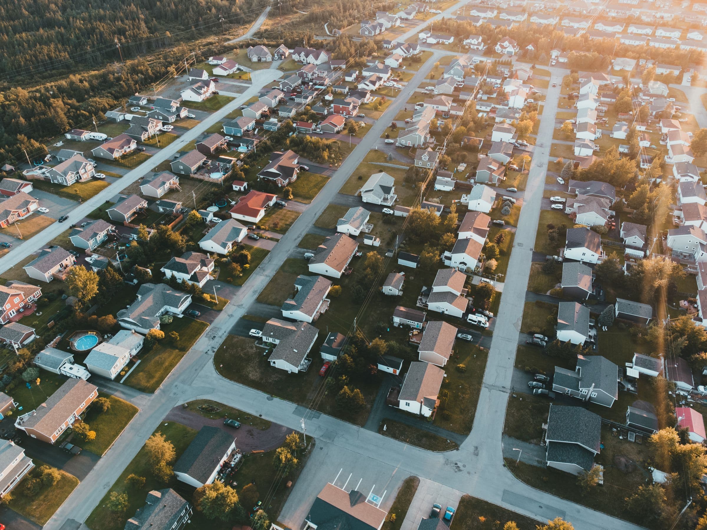 Golden-hour aerial view of a suburban neighborhood with alleys behind the homes.